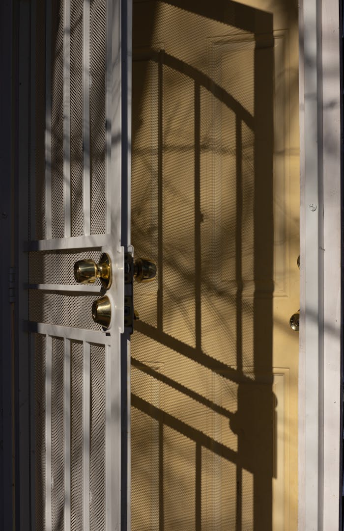 Half opened gate with chain link and metal bars and wooden door on sunny day